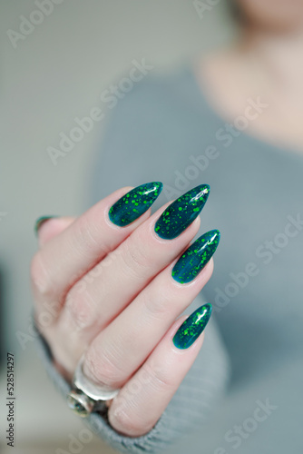 Woman's hand with long nails and bright yellow green thermo manicure with bottles of nail polish photo