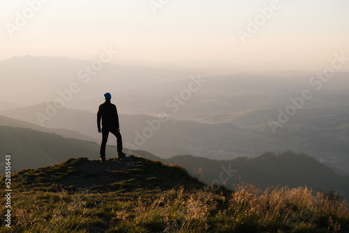 Man enjoys a view of the autumn landscape standing on top of a mountain