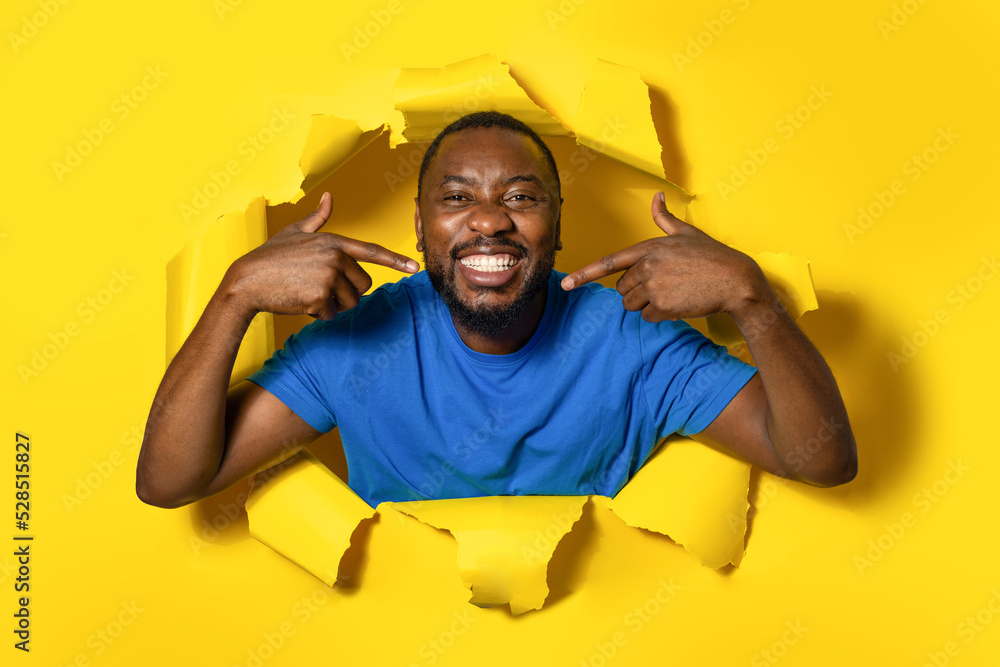 Shot of smiling african american man standing in torn paper hole