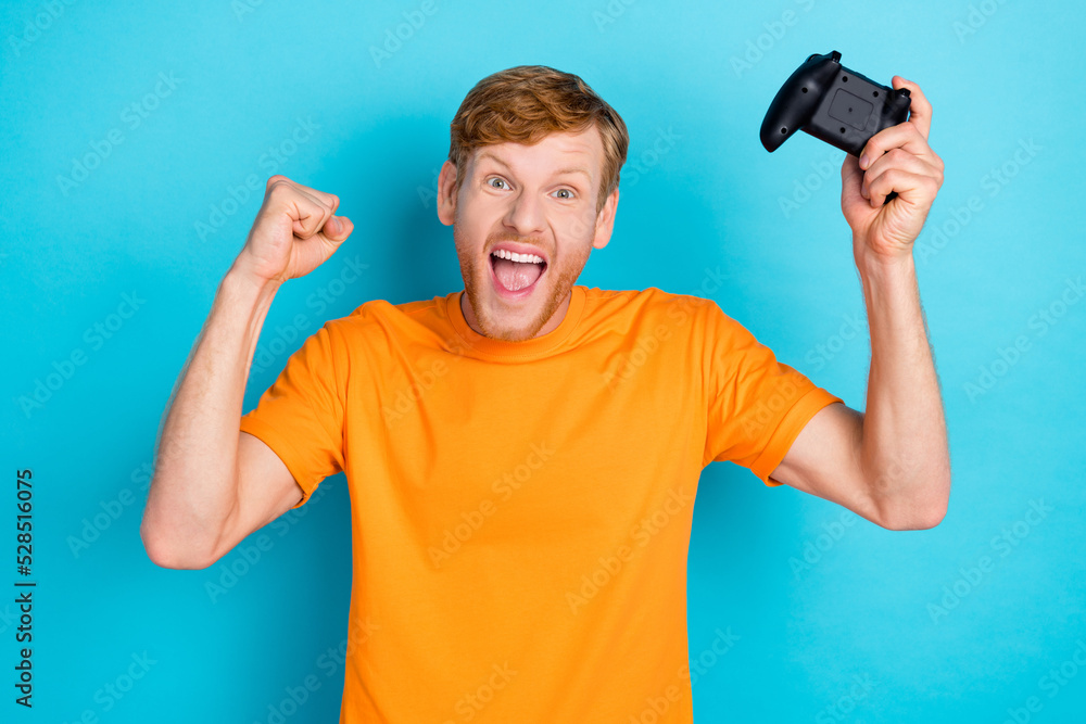 Photo of hooray red hair guy playstation yell wear orange t-shirt isolated on bright blue color background Photo of hooray red hair guy playstation yell wear orange t-shirt isolated on bright blue color background