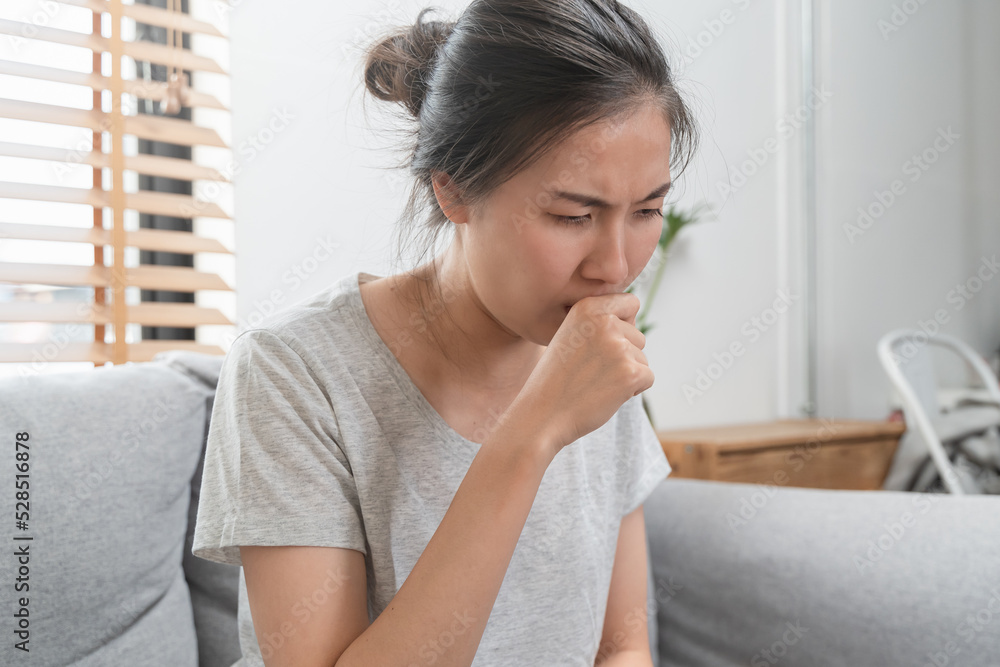 asian woman coughing and feeling sore throat at home. asian woman coughing and feeling sore throat at home.