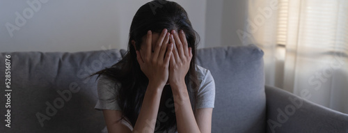 Canvas Print Asian woman covering her face feeling sorrow and depressed sit in the dark bedro