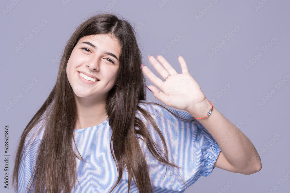 Smiling girl with thick eyebrows waving her hand Smiling girl with thick eyebrows waving her hand