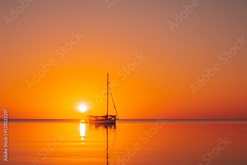 Beautiful view of a sailing boat silhouette in the ocean at sunset in Southern Belize.