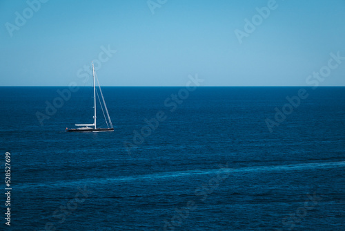 Yacht in the blue sea background, small sailboat adventure, seascape, boat travel through on the deep ocean horizon. © Pykodelbi