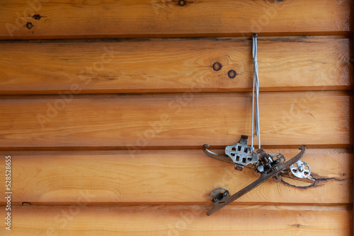 Old leather skates hang on a wooden wall made of timber. Antique, rare skates hang on a wall made of round wooden beams. Copy space. Memories, nostalgia for childhood