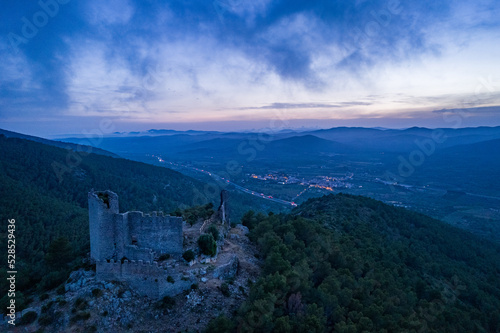 Fotografía aérea del castillo de Santa Magdalena de Pulpis, situado en la sierra de Irta, con nubes bajas durante la hora azul. photo