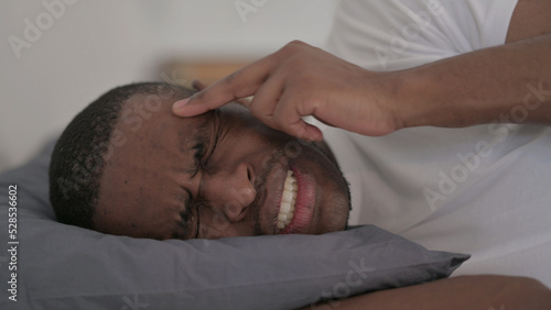 Close up of African Man having Headache while Sleeping in Bed