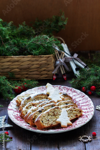 Christmas stollen with dried fruits, nuts and spices, Christmas decorations on a dark wooden background. Rustic style.