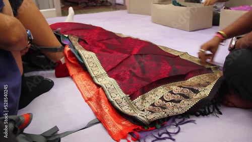 Silk factory vendor unfolding colorful sarees in showroom floor for customers in Varanasi, India. Retail store business, buy, shopping concepts