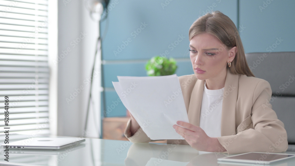 Businesswoman Reading Reports while Sitting in Office Businesswoman Reading Reports while Sitting in Office