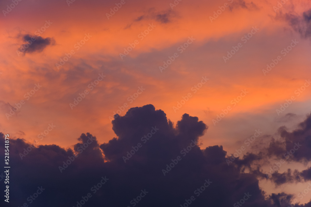 Dark clouds against a scarlet pink sky during sunset.