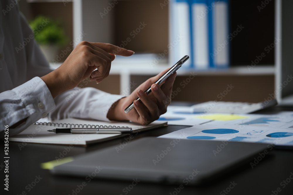 Close up of business hands working smartphone and calculating on financial and accounting graft and chart in office space. Close up of business hands working smartphone and calculating on financial and accounting graft and chart in office space.