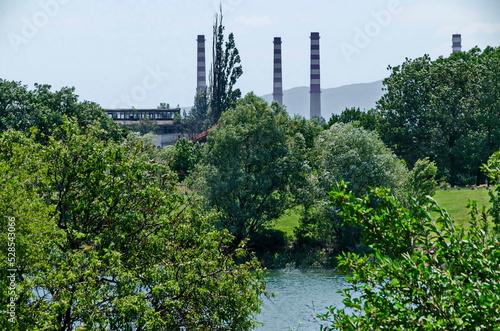 Spring green fresh trees and lake in residential area Drujba against the background of the chimneys of the Thermal Power Plant, Sofia, Bulgaria 
