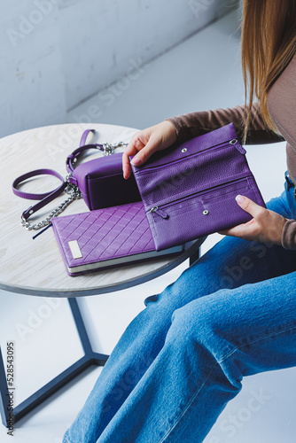 A purple leather bag in a girl's hand. Woman with luxury bag.