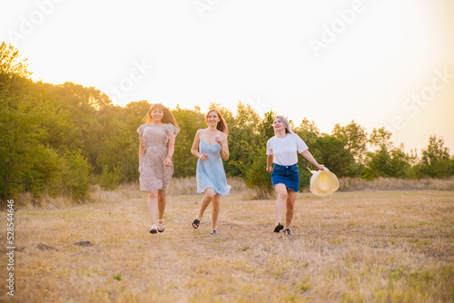A group of girlfriends jumps and runs outdoors. A group of female friends hugs and enjoys the sunset in nature. Laughter, smiles and joy.