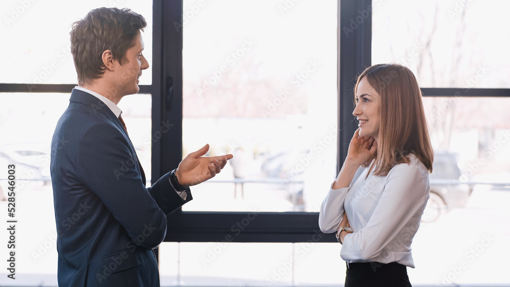 side view of employer pointing with hand while talking to positive woman on job interview.