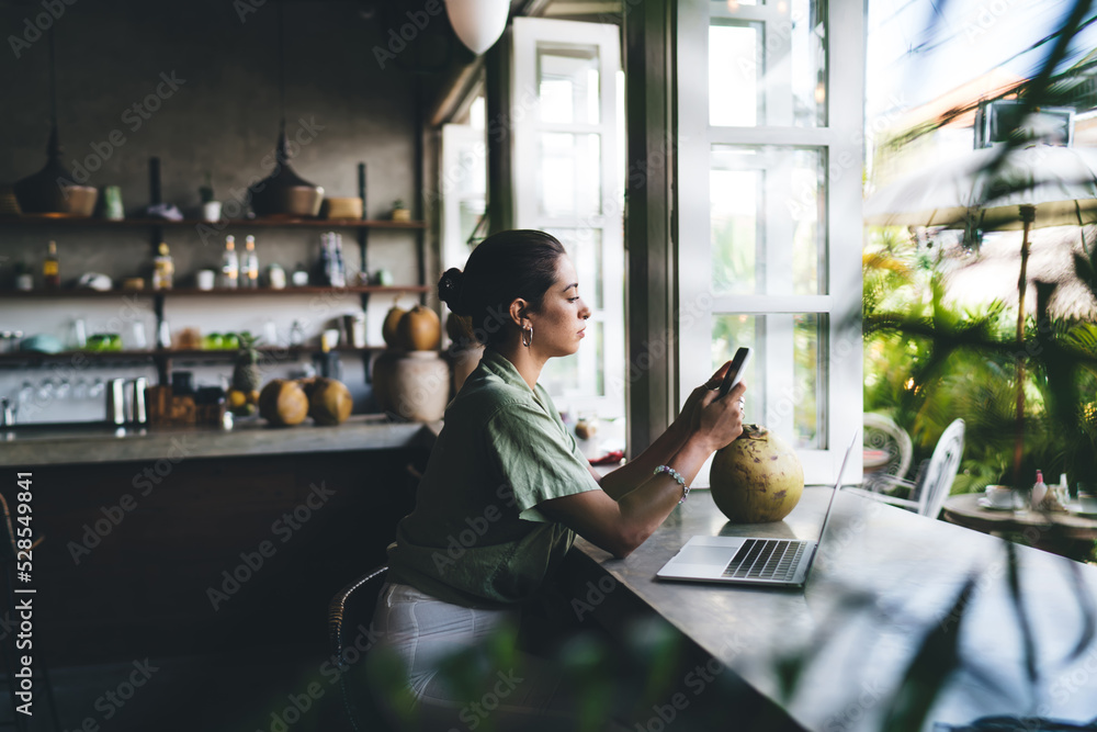 Young millennial woman in summer cloth sitting with smartphone device near laptop computer.Female freelancer using technology and internet for communication. application for social network and banking