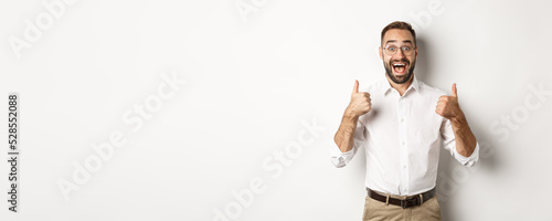 Stampa su tela Excited man in glasses showing thumbs up and looking amazed, agree and approve s