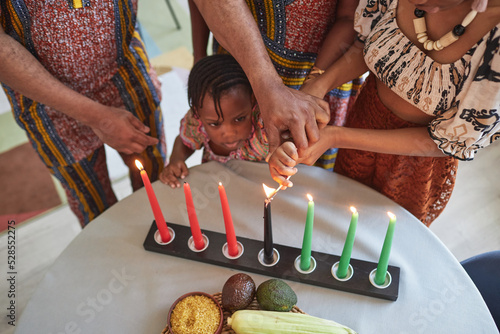 High angle view of African little girl burning candles on table with the help of her family photo