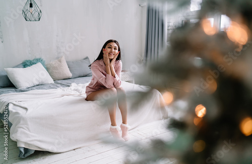 Asian woman sit on bed and look on christmas tree