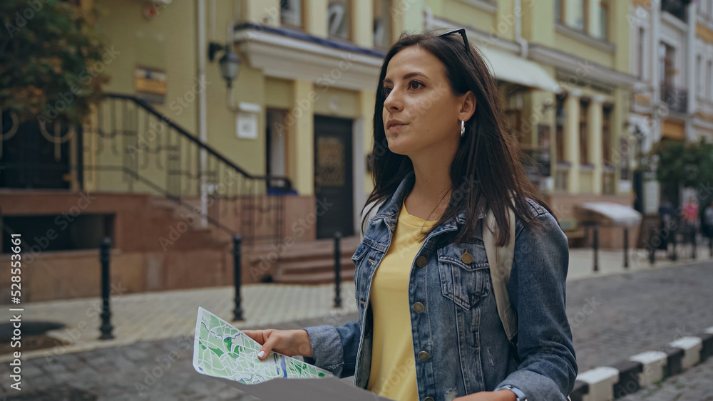 Fototapeta premium Traveler holding map and looking away on urban street.