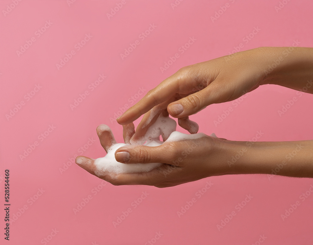 Female hands washing with soap on pink background Female hands washing with soap on pink background