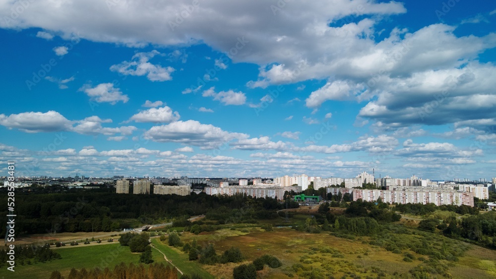 City with high-rise buildings. Park area in the foreground. Blue sky with clouds. Aerial photography.