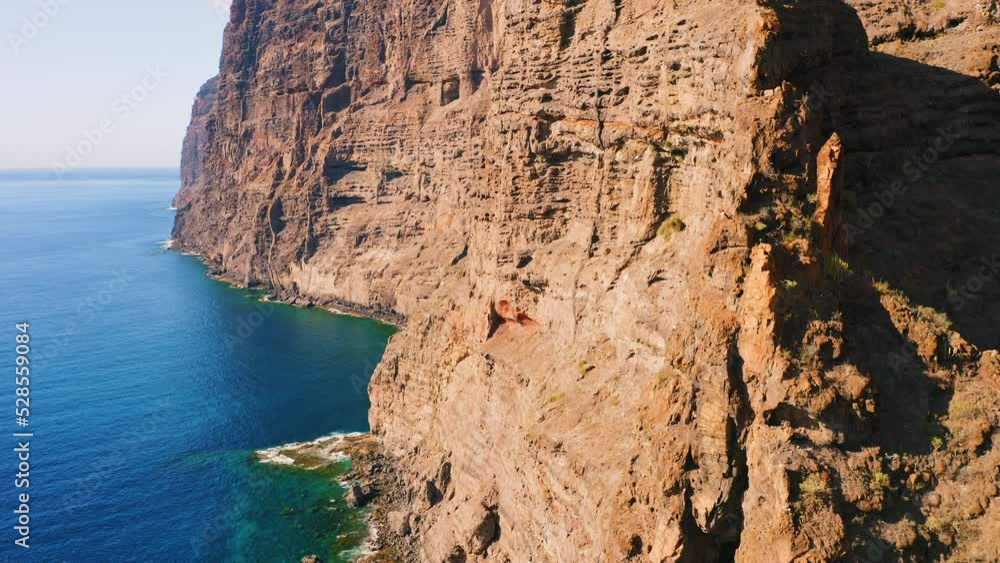 Beautiful nature, Tenerife Island. Travel summer vacation concept. Huge rocks barren mountains. Deep azure transparent water. Aerial tilt up footage of rocky empty cliff in ocean. Atlantic sea shore. Beautiful nature, Tenerife Island. Travel summer vacation concept. Huge rocks barren mountains. Deep azure transparent water. Aerial tilt up footage of rocky empty cliff in ocean. Atlantic sea shore.