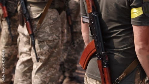 A row of Ukrainian soldiers line up at the checkpoint, wearing military uniforms and holding Kalashnikov assault rifles behind their backs.