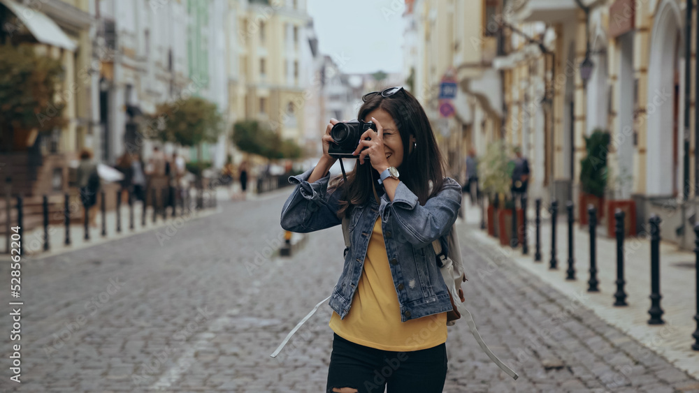 Young traveler taking photo on retro camera on urban street.