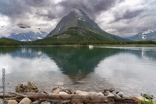 Swiftcurrent Lake in Glacier National Park as a shuttle boat sails across on a cloudy day