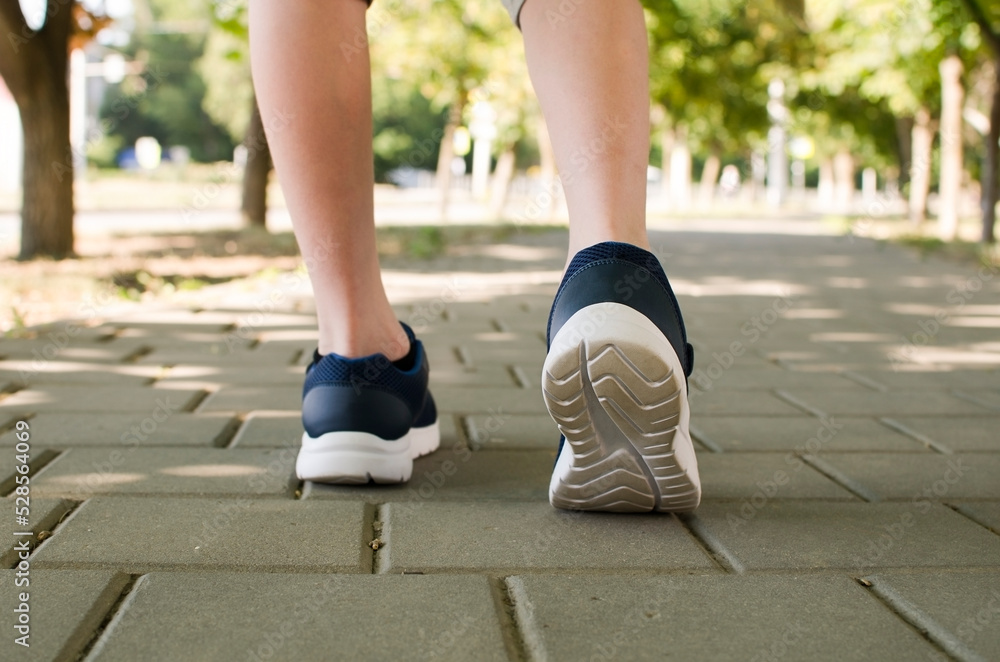 a child in sneakers walks along the sidewalk on a sunny day a child in sneakers walks along the sidewalk on a sunny day