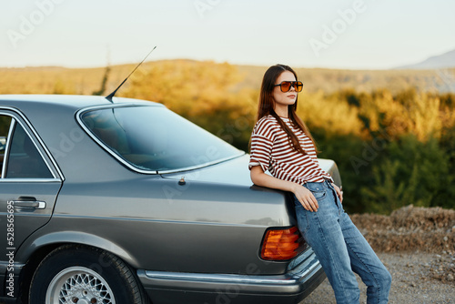 Stylish woman in striped t-shirt sunglasses and jeans near gray car in nature © SHOTPRIME STUDIO