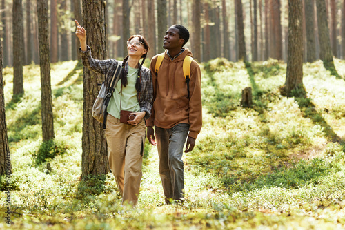 Multiethnic couple looking at beautiful nature while walking together in the forest