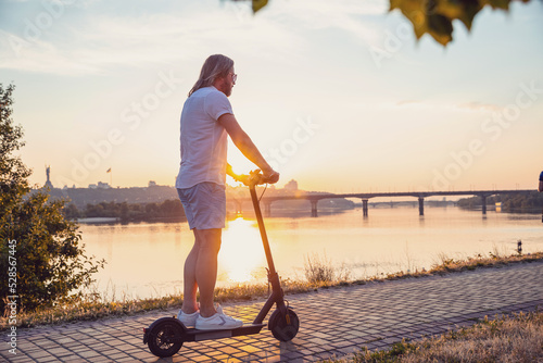 Caucasian man riding electric scooter at sunset photo