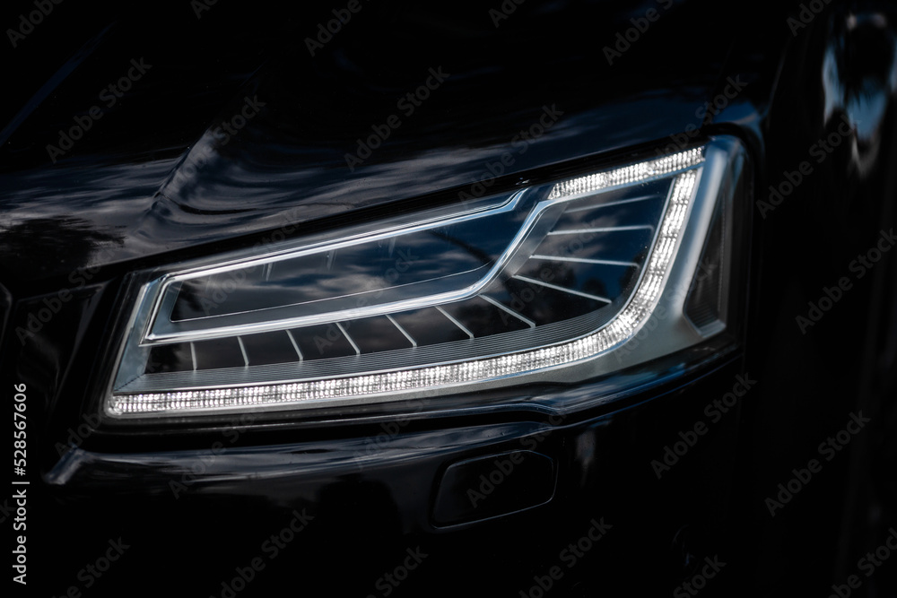 Headlight of Modern Prestigious Black Car Close Up.