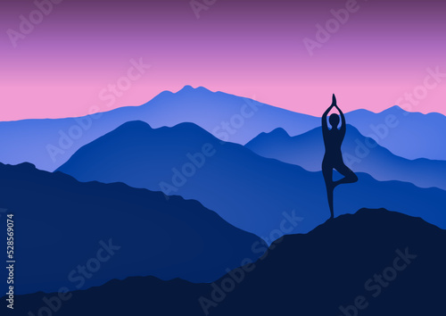Yoga woman standing in tree pose in mountains at beautiful sunrise.