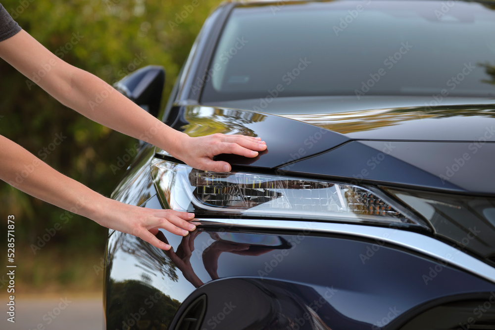 Female driver hands checking headlight of her new car. Purchase of vehicle concept