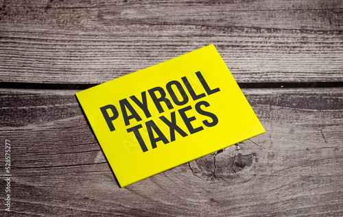 Payroll Taxes written on yellow paper note