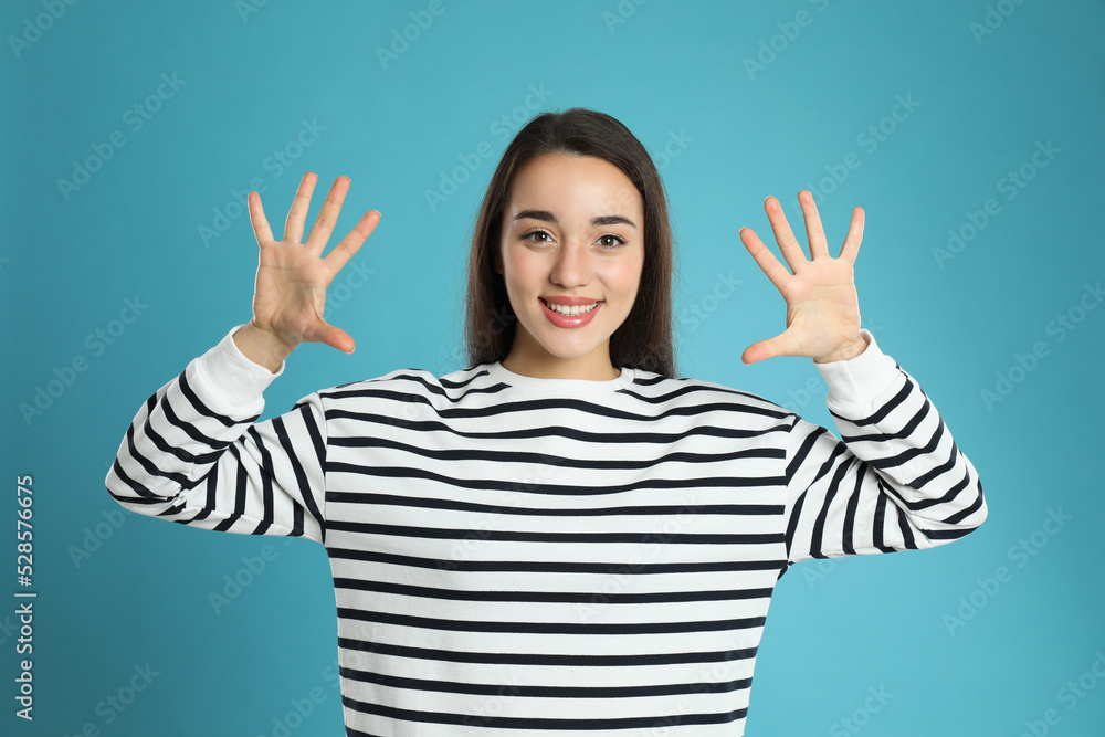 Woman showing number ten with her hands on light blue background Woman showing number ten with her hands on light blue background