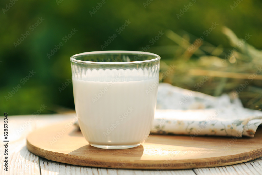 Glass of tasty fresh milk on white wooden table against blurred background Glass of tasty fresh milk on white wooden table against blurred background