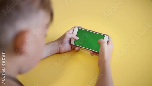 Chroma key mock-up on smartphone in hand. teenage boy use phone with green screen layout, color key, Watch content, play game. Use green screen for copy space closeup. Slow motion.