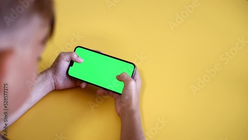 green screen. The child is holding a Smartphone in hand Close-up playing a game. phone with blank green screen mock up display for advertising. Slow motion.