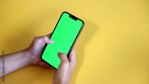 Chroma key mock-up on smartphone in hand. teenage boy use phone with green screen layout, color key, Watch content, play game. Use green screen for copy space closeup. Slow motion.