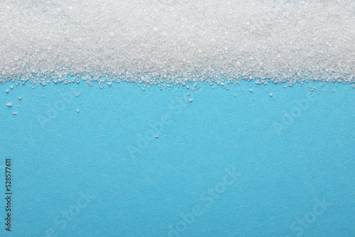 Granulated sugar on light blue background, top view. Space for text