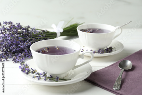 Fresh delicious tea with lavender and beautiful flowers on white wooden table