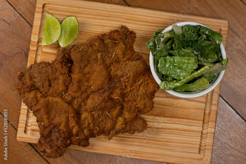 Milanese with topping. Milanesa covered with arugula, tomatoes, cheese. Breaded meat. Italian food. Fried meat. Beef, chicken meat, pork meat.