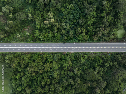Fototapeta Naklejka Na Ścianę i Meble -  Aerial view from drone of straight two lane road with both sides is lush green woodland.