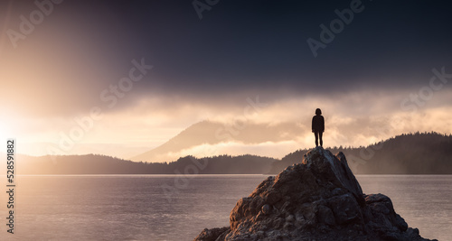 Adventurous Woman Hiking on the Rocky Coast with Mountains and Dramatic Sunset Sky. Adventure Composite. 3d Rendering Rocks. Background from West Coast of British Columbia, Canada. © edb3_16